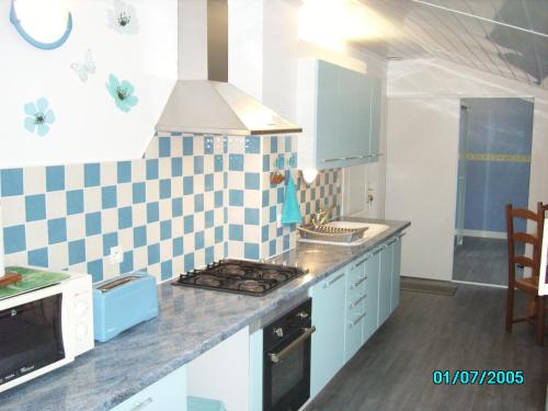 - une cuisine avec du carrelage bleu et blanc sur le mur dans l'établissement CHEZ MARTINE Appt climatisé 1 Chambre, à Capbreton