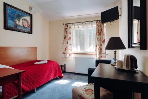 a hotel room with a red bed and a desk at Hotel Legenda in Toruń