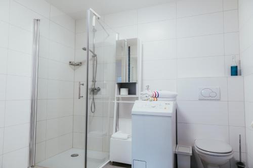a white bathroom with a shower and a toilet at Ferienwohnung "Köhler" am Bodensee in Meckenbeuren
