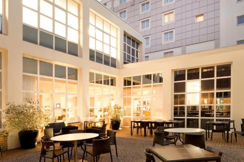 un grand bâtiment avec des tables et des chaises dans la cour dans l'établissement Novotel Lille Centre Grand Place, à Lille