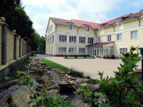 a large white building with a stone courtyard at Zhyttedar in Ulanov