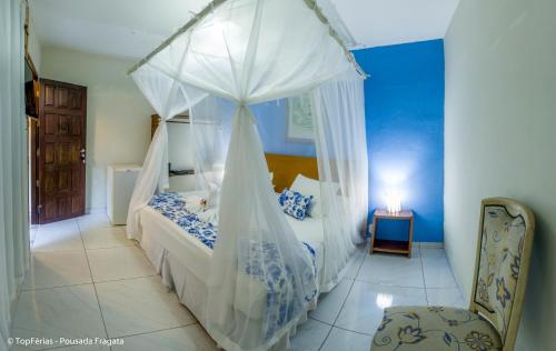 een slaapkamer met een hemelbed en een stoel bij Pousada Fragata - Arraial D Ajuda - Melhor Localização e Atendimento in Arraial d'Ajuda