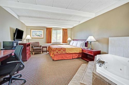 a hotel room with a bed and a bath tub at Travelodge by Wyndham Iowa City in Iowa City