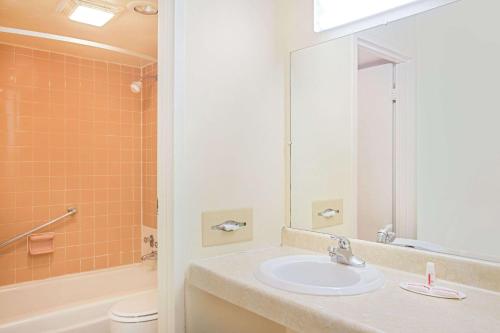 a bathroom with a sink and a toilet and a mirror at Days Inn by Wyndham Bristol Parkway in Bristol