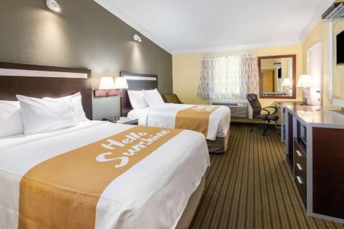 a hotel room with two beds and a desk at Days Inn by Wyndham Nanuet / Spring Valley in Nanuet