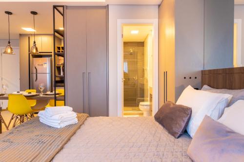 a bedroom with a bed and a bathroom with a table at Luxuoso Apto Em Frente Ao Shopping Curitiba - Piscina, Academia e Sauna in Curitiba
