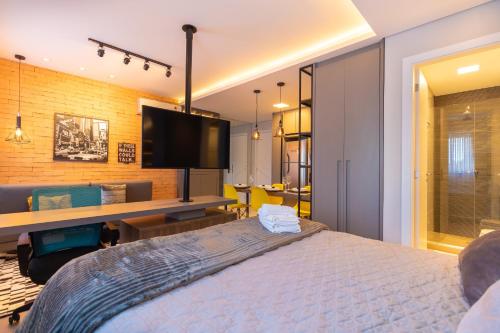 a bedroom with a bed and a flat screen tv at Luxuoso Apto Em Frente Ao Shopping Curitiba - Piscina, Academia e Sauna in Curitiba