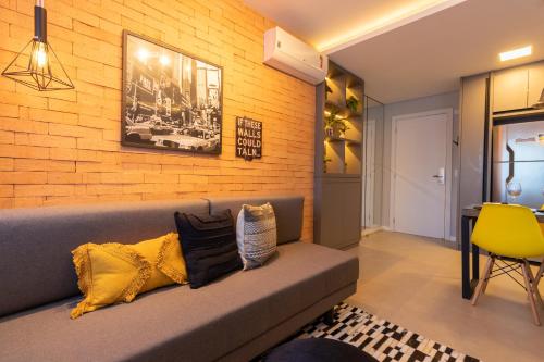 a living room with a couch and a brick wall at Luxuoso Apto Em Frente Ao Shopping Curitiba - Piscina, Academia e Sauna in Curitiba
