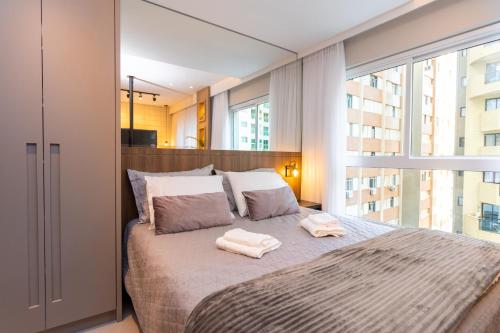 a bedroom with a large bed with two towels on it at Luxuoso Apto Em Frente Ao Shopping Curitiba - Piscina, Academia e Sauna in Curitiba