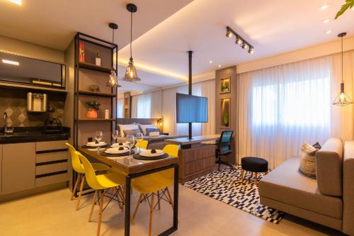 a living room and kitchen with yellow chairs and a table at Luxuoso Apto Em Frente Ao Shopping Curitiba - Piscina, Academia e Sauna in Curitiba