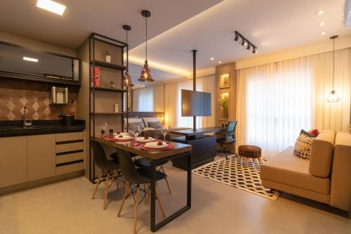 a kitchen and living room with a table and a couch at Luxuoso Apto Em Frente Ao Shopping Curitiba - Piscina, Academia e Sauna in Curitiba