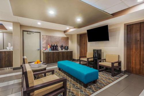 a hotel room with a blue couch and a tv at La Quinta by Wyndham Jamestown in Jamestown