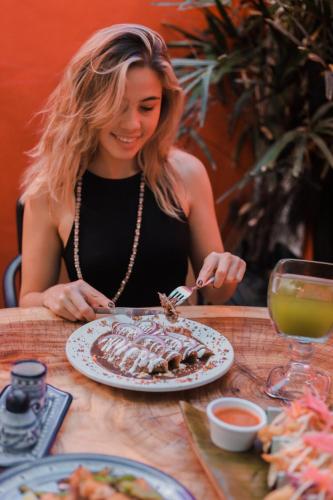 a woman sitting at a table with a plate of food at Hotel Casa de las Flores in Playa del Carmen