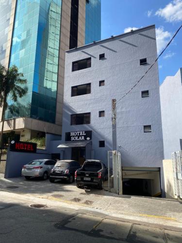 a parking lot with cars parked in front of a building at Hotel Solar Bela Vista in Sao Paulo