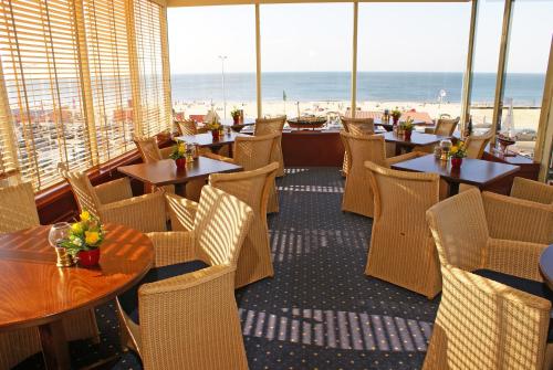 un restaurante con mesas y sillas y vistas a la playa en Boulevard Hotel Scheveningen en Scheveningen