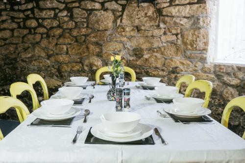 a long table with white dishes on it with yellow chairs at Finest Retreats - Britannia House B&B - Double Room in Carleen