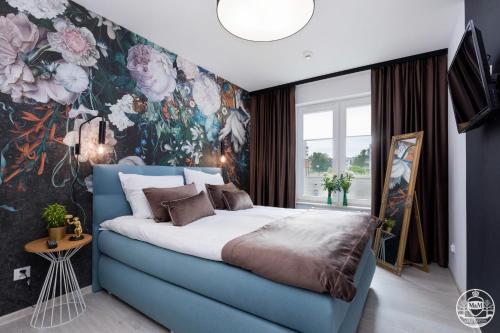 a bedroom with a blue bed with a floral wallpaper at Park Design - Apartments M&M (Polanki Park) in Kołobrzeg