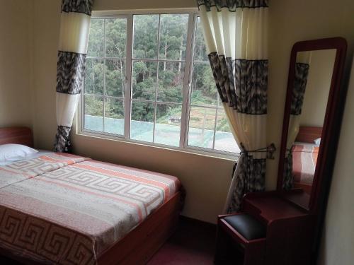 a bedroom with a bed and a large window at Keshiya Holiday Home in Nuwara Eliya