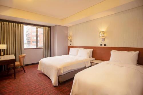 a hotel room with two beds and a desk at Hej Taipei Arena Hotel in Taipei