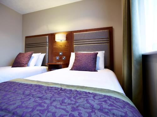 a hotel room with two beds with purple pillows at The Briar Court Hotel in Huddersfield
