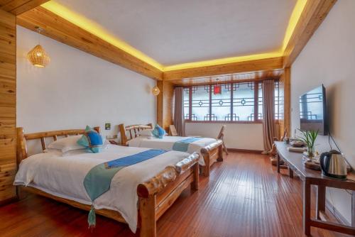 two beds in a room with wooden floors and ceilings at Ridge Inn in Longsheng