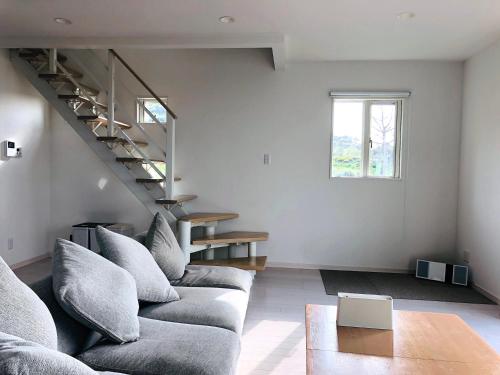 a living room with a couch and a staircase at Saraswati in Nakijin