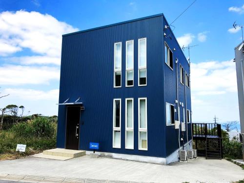 a blue building with white windows on the side of it at Saraswati in Nakijin
