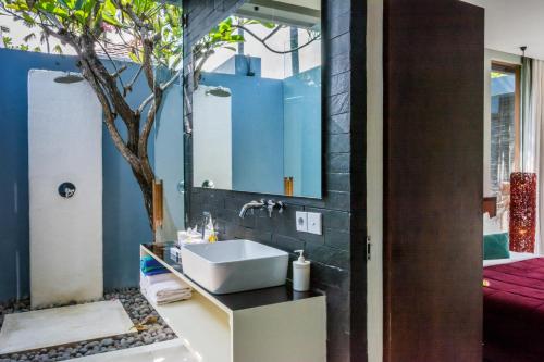 a bathroom with a sink and a tree in it at Kembali Villas in Seminyak
