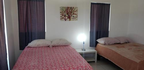 Dormitorio pequeño con cama y mesa con lámpara en Casa cerca de Estero Beach, en Ensenada