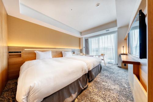 a hotel room with a large bed and a flat screen tv at Umekoji Potel KYOTO in Kyoto