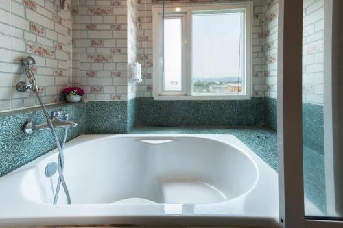 a bath tub in a bathroom with a window at The Lilly Hotel in Chiang Mai