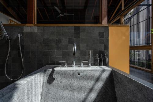 a bath tub with a shower and a sink at The Saren in Tanah Lot