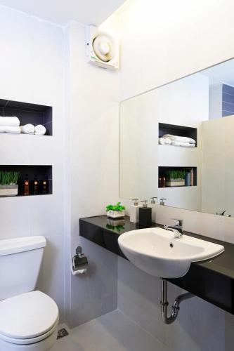 a bathroom with a sink and a toilet and a mirror at @Home Residence in Bang Kapi