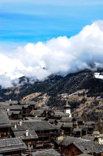 a bunch of buildings with clouds in the mountains at Luxury Grimentz Apartment in Grimentz