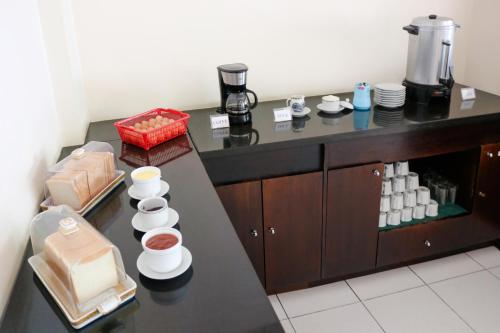 a kitchen with a counter with cups and plates at LeGreen Suite Ratulangi in Ambon