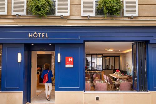 a woman walking in front of a hotel at Hôtel des Arts Montmartre in Paris