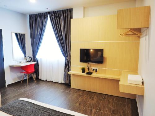 Habitación de hotel con TV y escritorio con silla roja. en The Tree Hotel, en Muar