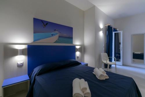 a bedroom with a blue bed with white towels on it at Map Enjoy Rooms in San Vito lo Capo
