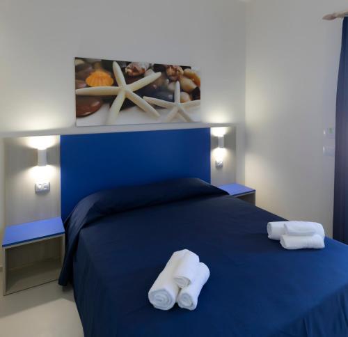 a bedroom with a blue bed with towels on it at Map Enjoy Rooms in San Vito lo Capo