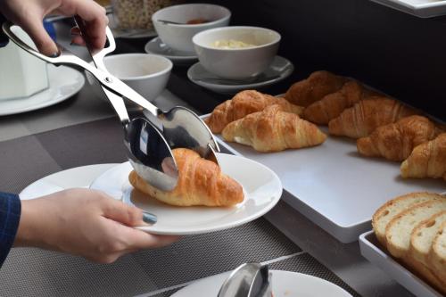 a person using tongs to eat a plate of pastries at Naki Suites @ Silvertown in Phnom Penh