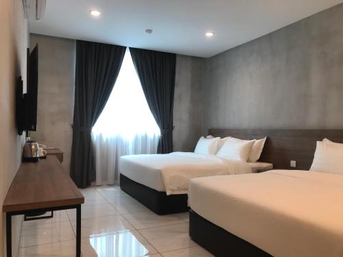 a hotel room with two beds and a window at Dandelion Inn in Simpang Pulai