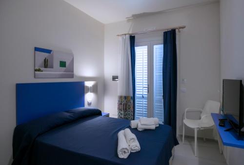 - une chambre avec un lit bleu et des serviettes dans l'établissement Map Enjoy Rooms, à San Vito Lo Capo