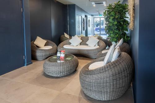a lobby with wicker chairs and couches and tables at Nightelier Narrabeen in Narrabeen