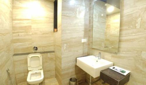 a bathroom with a sink and a toilet and a mirror at Hotel Lalit Inn in Khandala