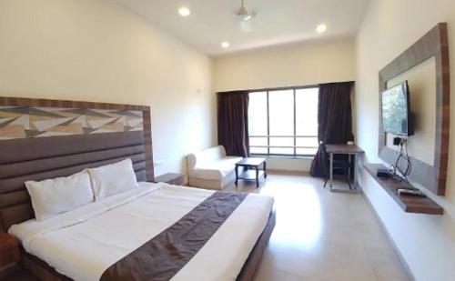 a bedroom with a large bed and a living room at Hotel Lalit Inn in Khandala