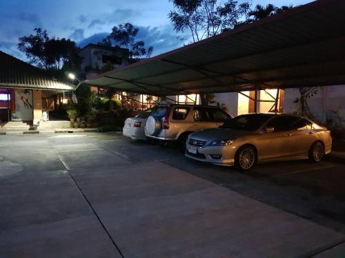 two cars are parked in a parking lot at โรงแรม เพนท์เฮ้าส์ รีสอร์ท เบตง in Betong