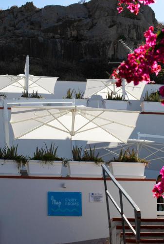 a white wall with potted flowers and an umbrella at Map Enjoy Rooms in San Vito lo Capo