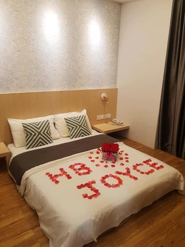 a bed with red roses on a white blanket at The Tree Hotel in Muar
