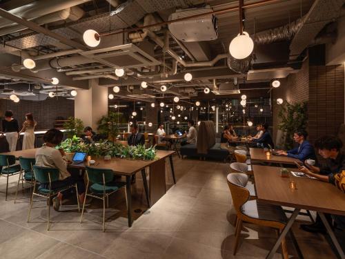 ein Restaurant mit Leuten, die an Tischen in einem Zimmer sitzen in der Unterkunft The Lively Osaka Honmachi in Osaka