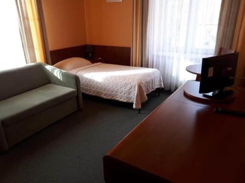 a hotel room with a bed and a couch and a television at Flisak in Sandomierz